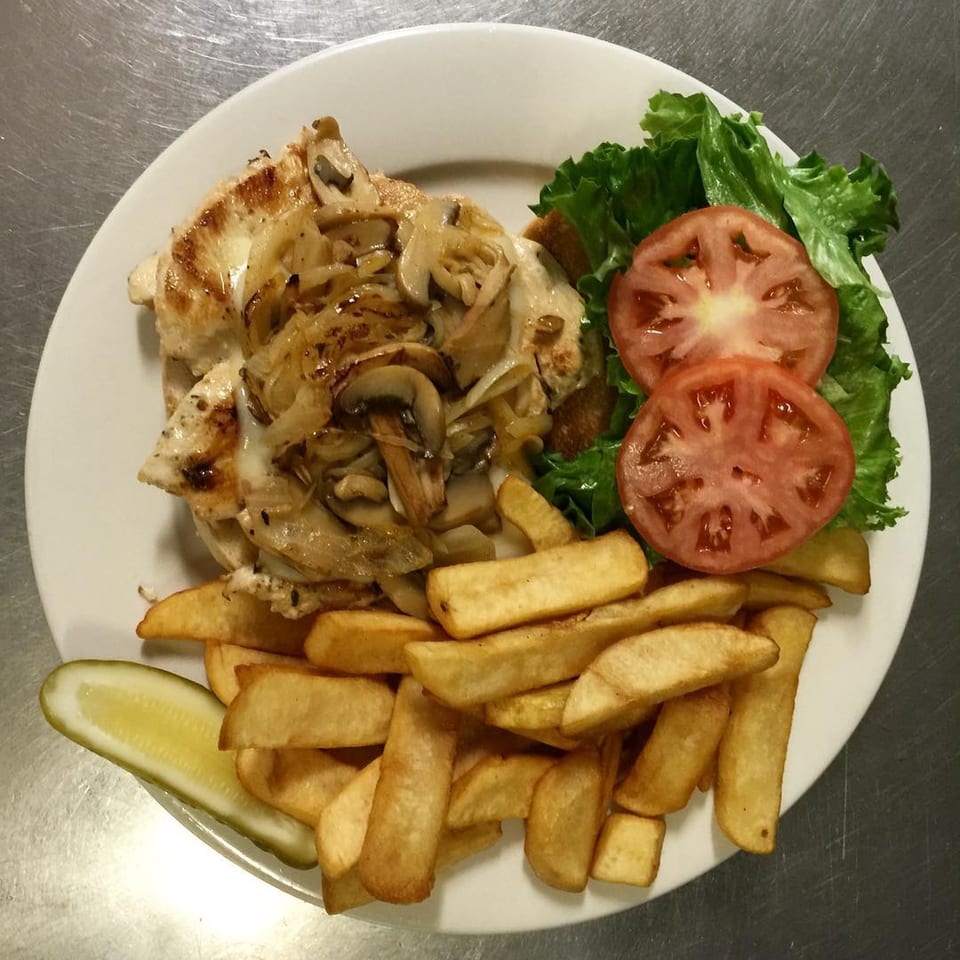 Grilled chicken with sautéed mushrooms and onions, served with fries, lettuce, tomato, and a pickle.